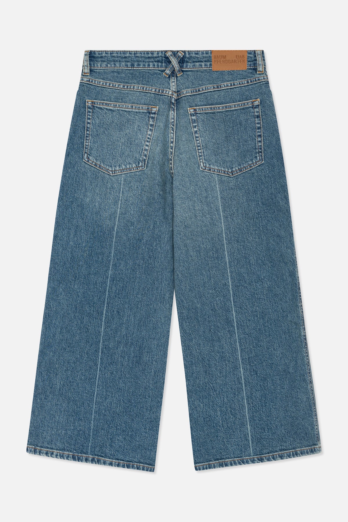 Close-up of the back of blue washed denim jeans, showing two patch pockets, orange topstitching and a tan branded waistband patch.
