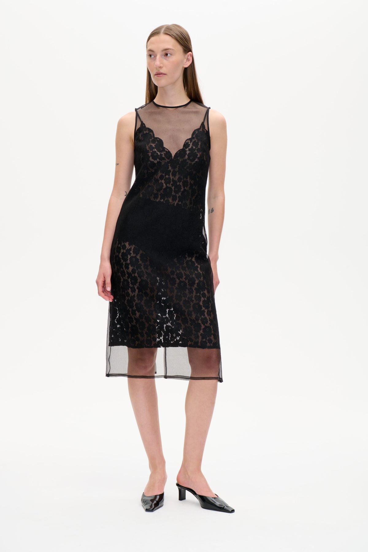 Front view of a black sleeveless lace dress with a sheer high-neck mesh panel and a long translucent overlay.