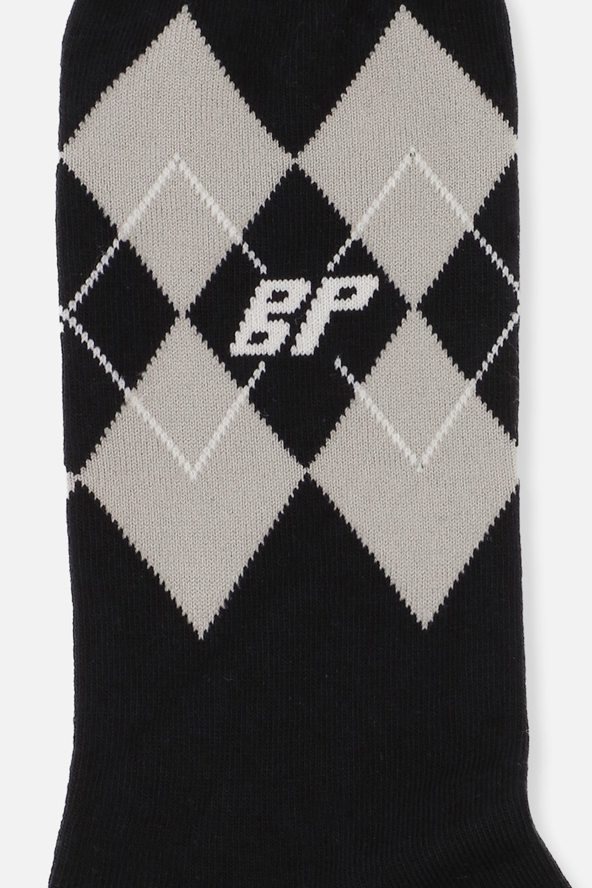 Gros plan d'une chaussette en maille noire à losanges argyle crème, ornée d'un petit monogramme discret.