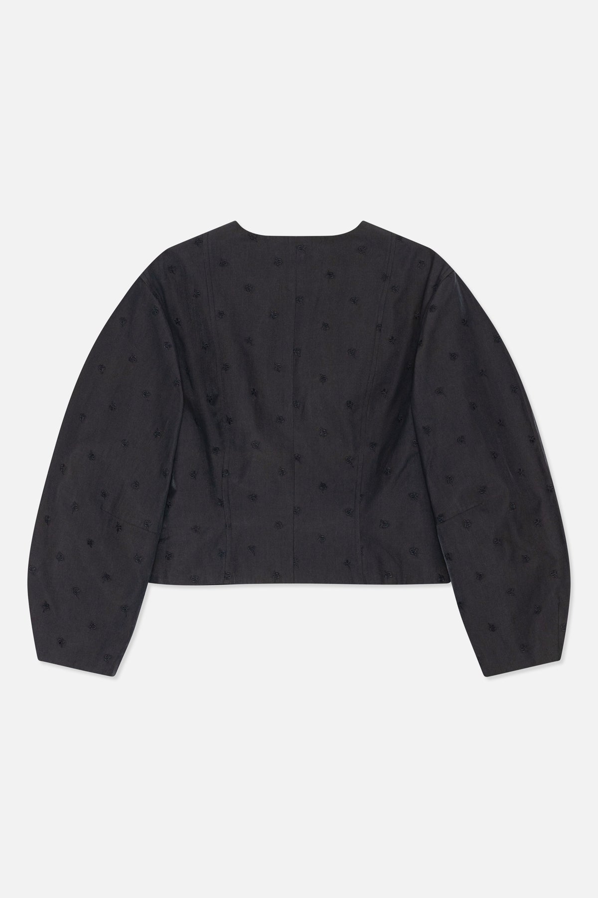 Back view of a dark charcoal long-sleeved top with a wide neckline, shaped panel seams and scattered tonal floral motifs.