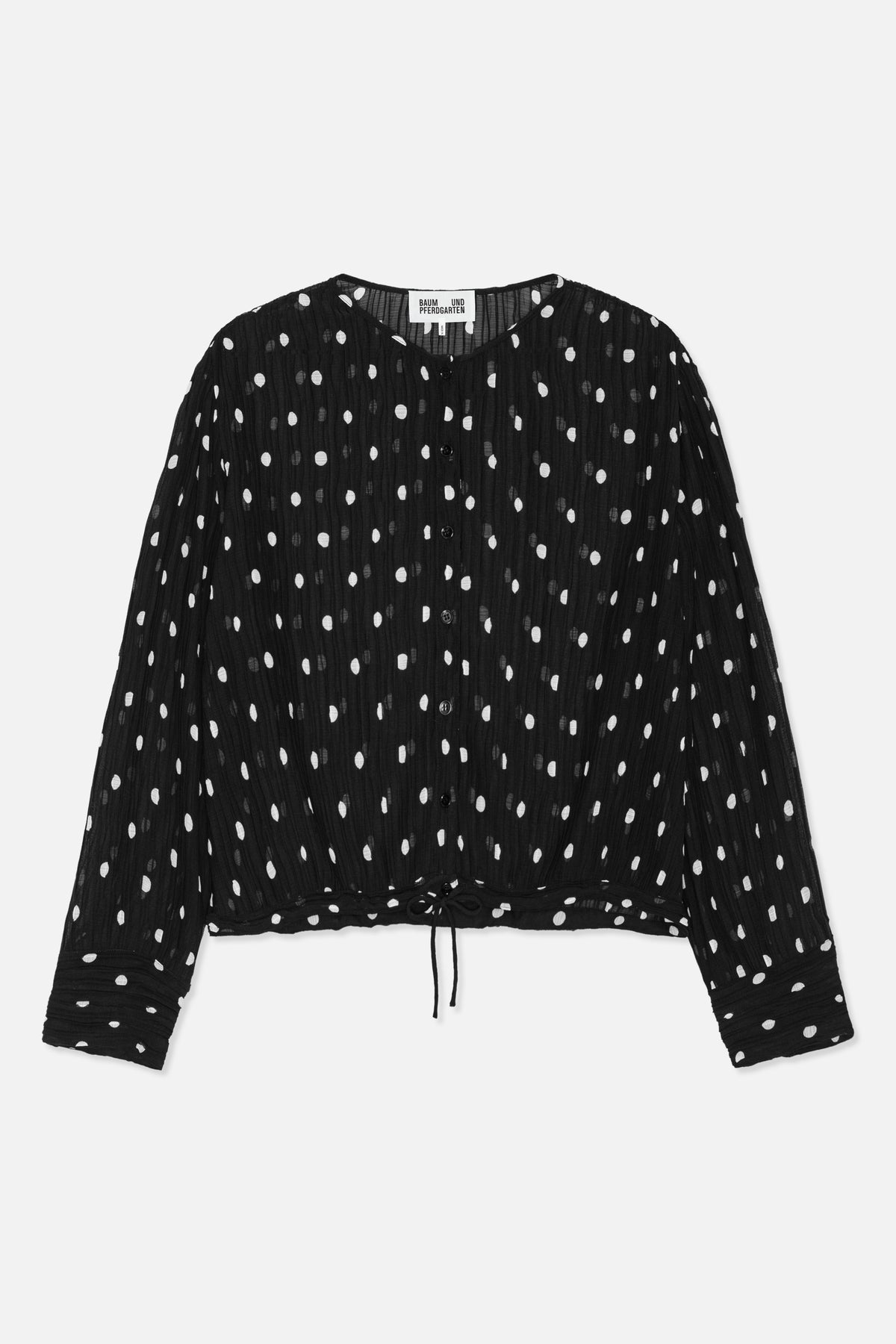 Front view of a black long-sleeved button-front blouse with white polka dots, a V-neck and adjustable drawstring hem.