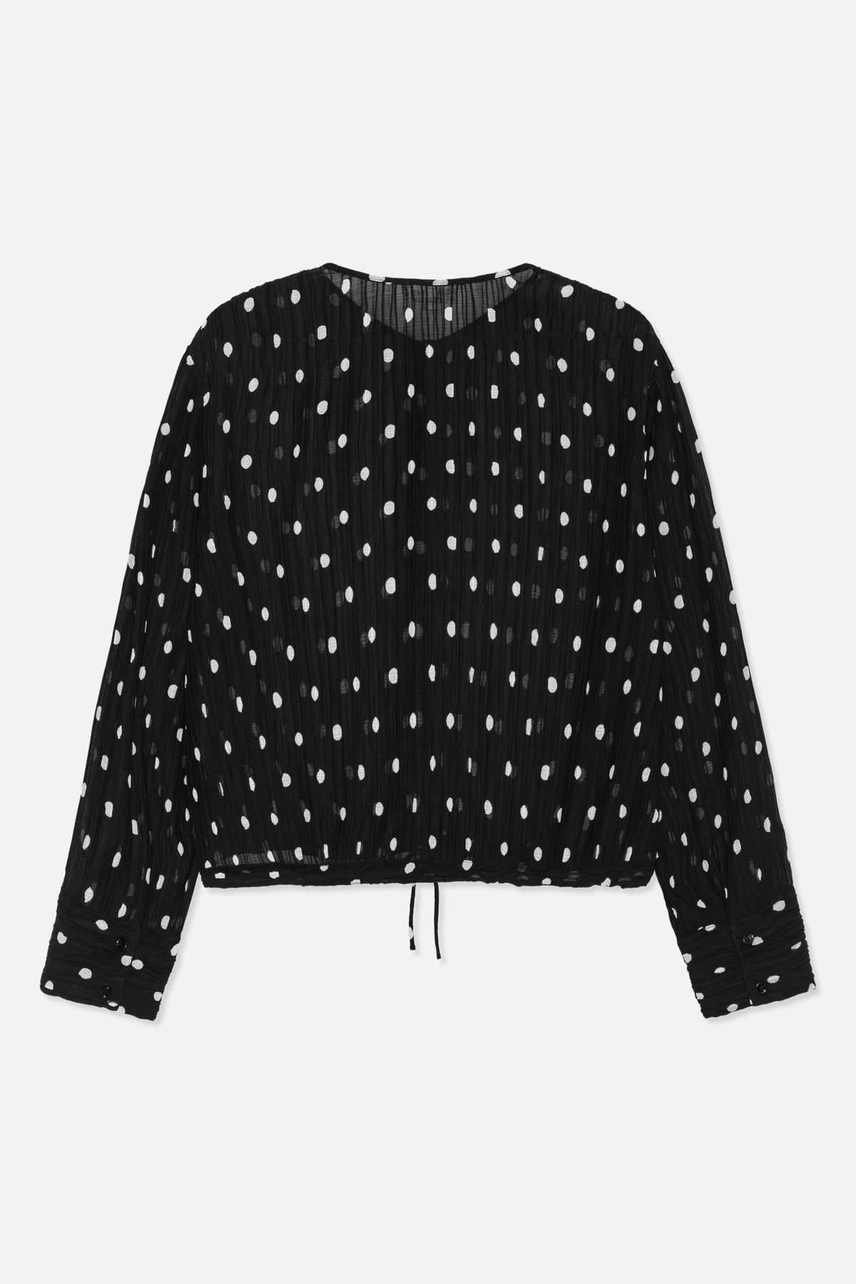 Front view of a black long-sleeved top with white polka dots, a round neckline, button cuffs and a drawstring hem.