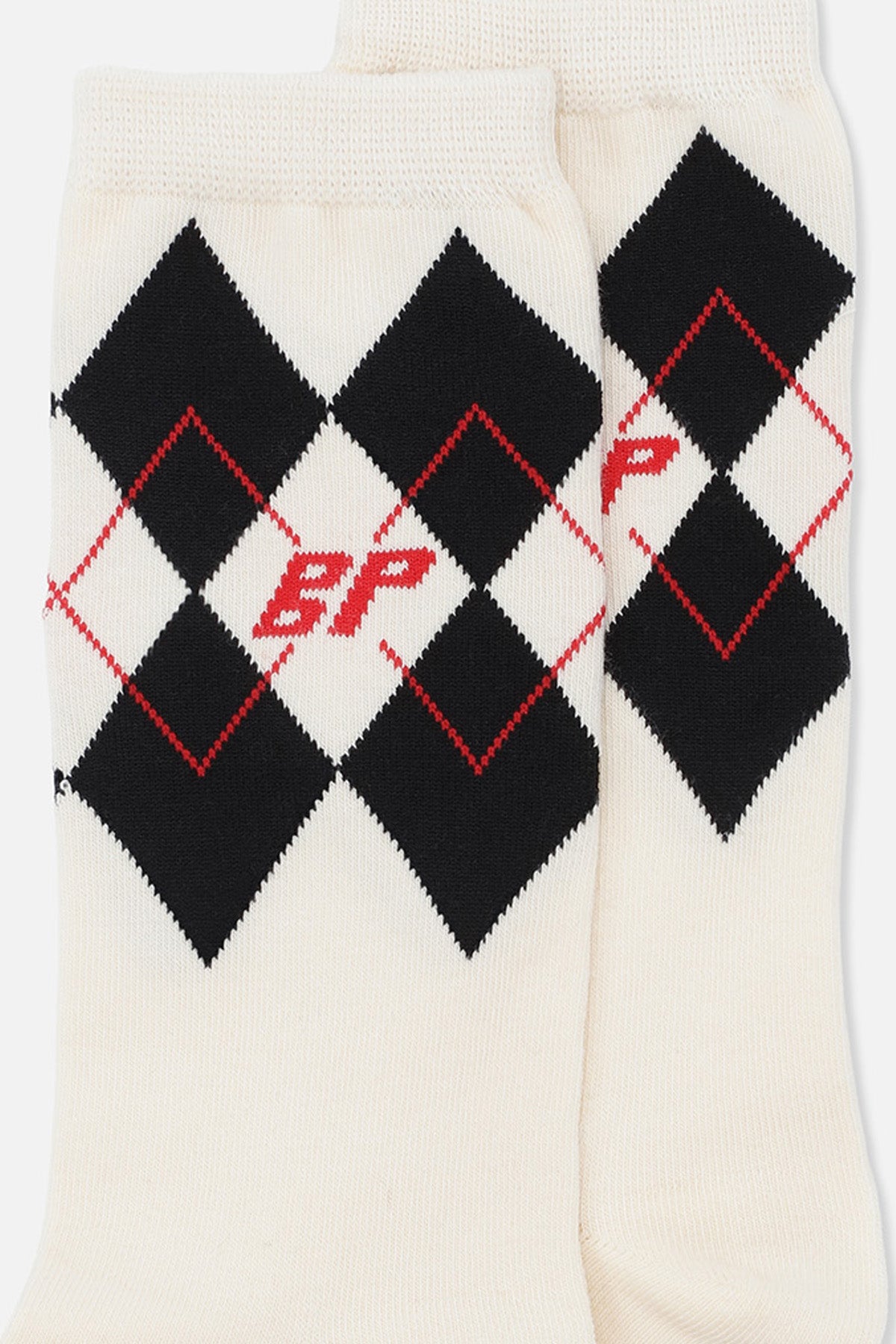 Pair of cream socks with black argyle diamonds, red outlined accents and red lettering, shown close up.